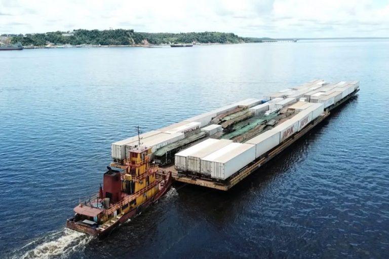 Empurrador rebocando uma balsa carregada de contêineres pelo rio Amazonas, próximo a Manaus