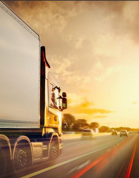 Caminhão de carga em movimento numa rodovia ao entardecer, com efeito de velocidade