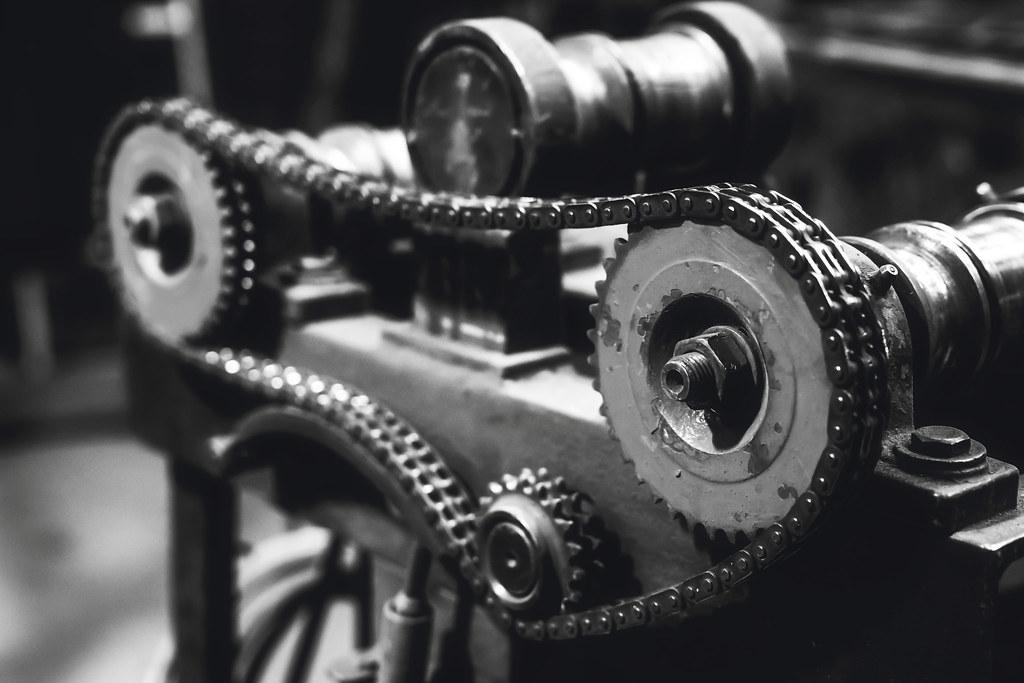 Detalhe de engrenagem e corrente de um equipamento industrial em funcionamento